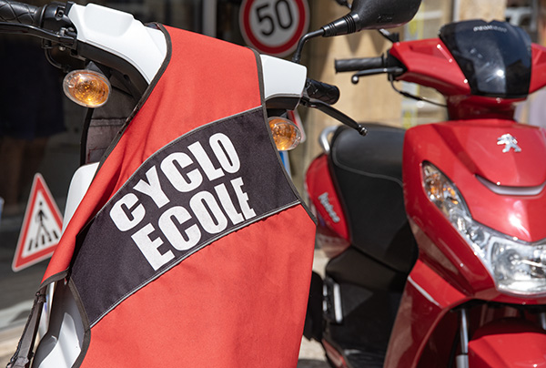Un gilet "Cyclo école" sur le guidon d'un scooter